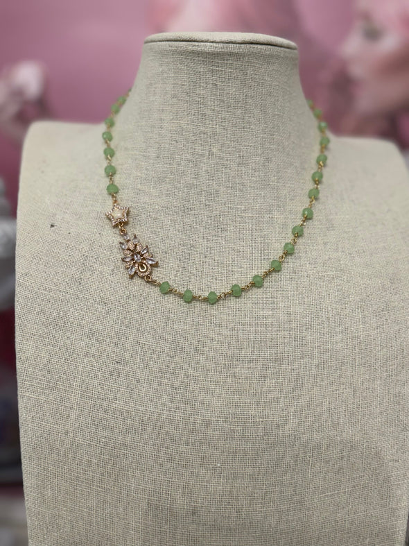 Elegant green chalcedony necklace with faceted stones and cubic zirconia charm on a beige display bust