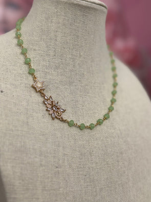 Elegant green chalcedony necklace with faceted stones and cubic zirconia charm on beige display bust